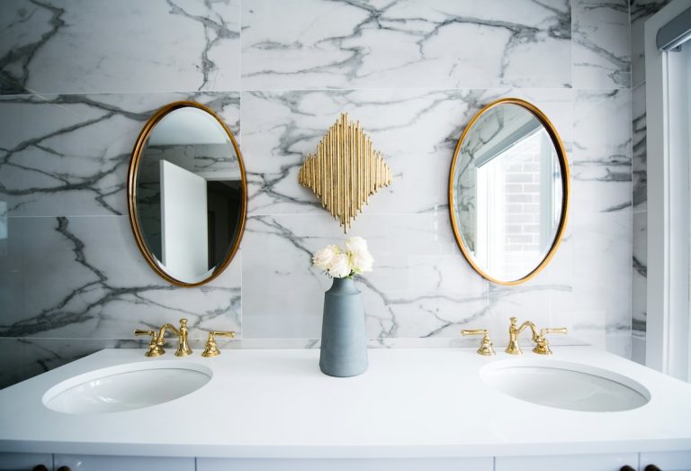 Marble bathroom with round brass mirrors